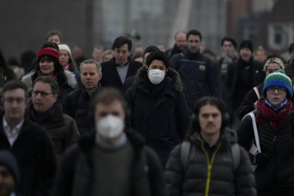 Workers walk over London Bridge towards the City of London financial district during the morning rush hour, in London, Monday, Jan. 24, 2022.