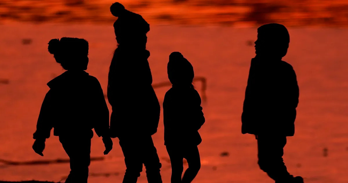 Kids are silhouetted against a pond at a park in Lenexa, Kansas, on Saturday, Dec. 26, 2020.