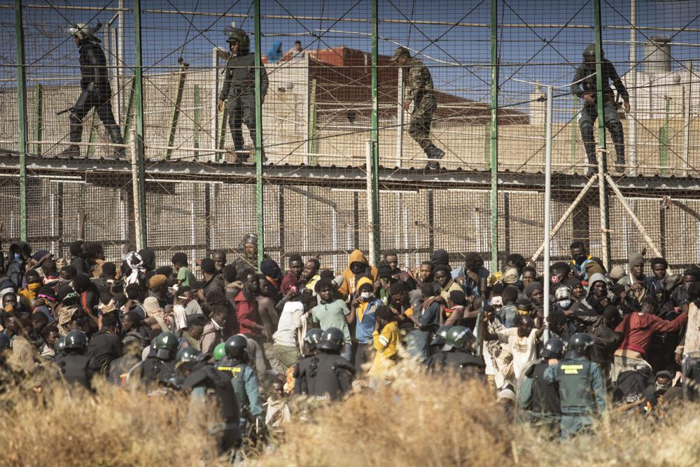 Riot police officers cordon off the area after migrants arrive on Spanish soil and crossing the fences separating the Spanish enclave of Melilla from Morocco in Melilla, Spain, Friday, June 2