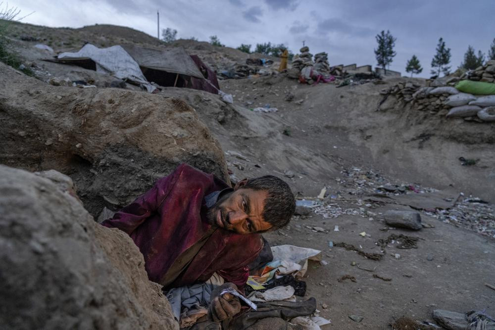 An Afghan drug addict smokes heroin on the edge of a hill in the city of Kabul, Afghanistan,Tuesday, June 7, 2022. (AP Photo/Ebrahim Noroozi/RSS)