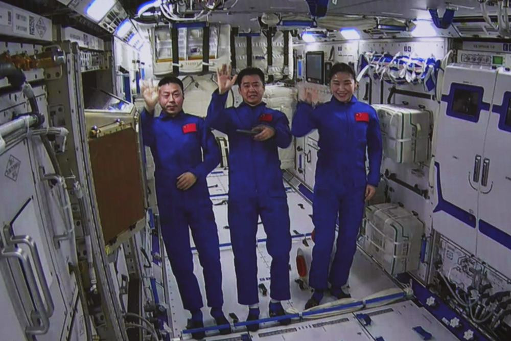 An image taken off the screen at the Beijing Aerospace Control Center shows Chinese astronauts from left, Cai Xuzhe, Chen Dong and Liu Yang wave from inside the Wentian lab module on Monday, 