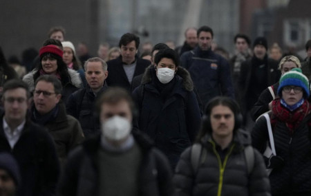 Workers walk over London Bridge towards the City of London financial district during the morning rush hour, in London, Monday, Jan. 24, 2022.