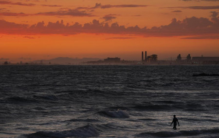 FILE - A man wades into the ocean at sunset on June 22, 2021, in Newport Beach, California.