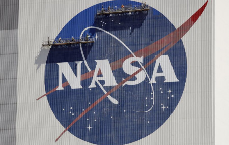 FILE - Workers on scaffolding repaint the NASA logo near the top of the Vehicle Assembly Building at the Kennedy Space Center in Cape Canaveral, Florida, Wednesday, May 20, 2020.