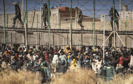 Riot police officers cordon off the area after migrants arrive on Spanish soil and crossing the fences separating the Spanish enclave of Melilla from Morocco in Melilla, Spain, Friday, June 2