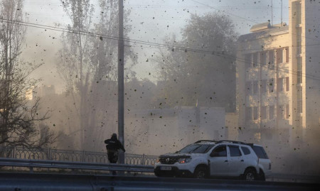 A police officer watches stone and earth debris flying through the air as Russian kamikaze drones hit the centre of the capital Kyiv, Ukraine, Monday, Oct 17, 2022. (AP/RSS Photo)