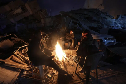 People warm up with fire in front of destroyed buildings in Antakya, southern Turkey, Wednesday, Feb. 8, 2023.  AP/RSS Photo