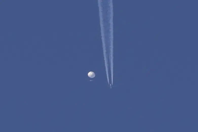 In this photo provided by Brian Branch, a large balloon drifts above the Kingstown, N.C. area, with an airplane and its contrail seen below it. AP/RSS Photo