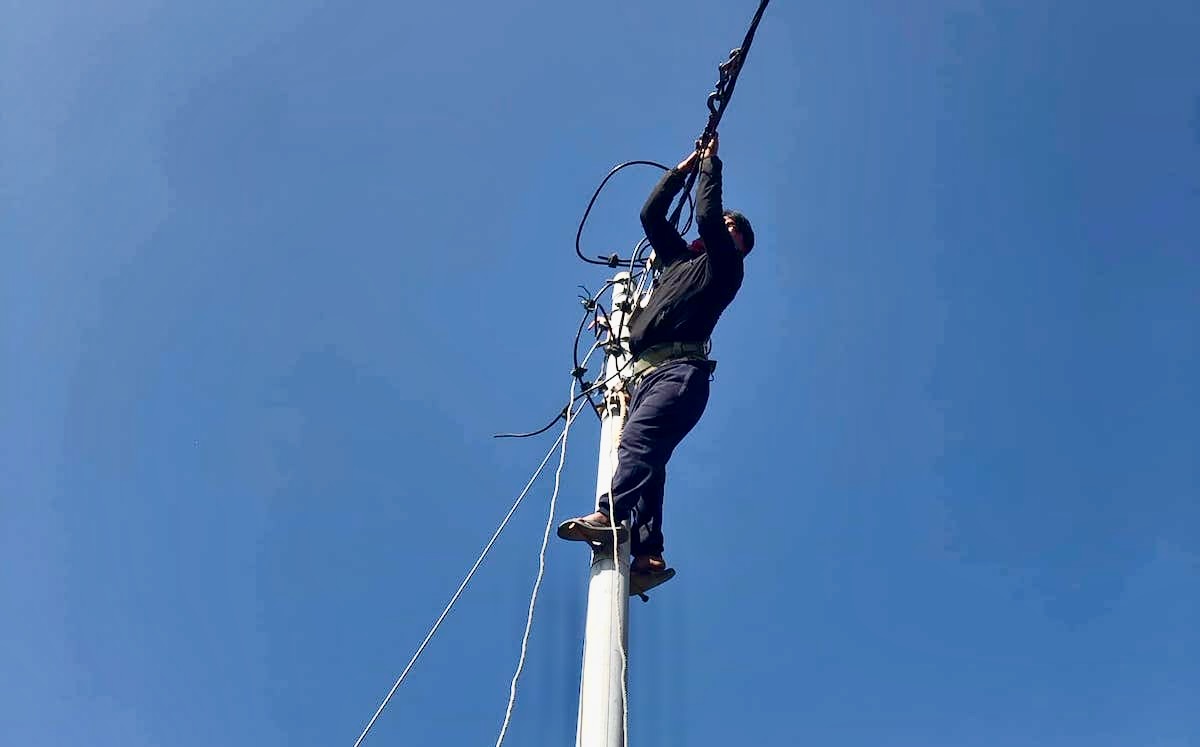 बिजुलीको खम्बामा चढेर तार तान्दै अनिल पहरी। तस्बिर स्रोत: अनिल