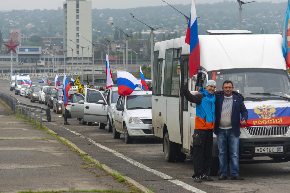 Two men pose for a photo in front of motorcade organized to support voting in a referendum in Luhansk, eastern Ukraine, Friday, Sept. 23, 2022. Voting began Friday in four Moscow-held regions of Ukraine on referendums to become part of Russia. AP/RSS Photo